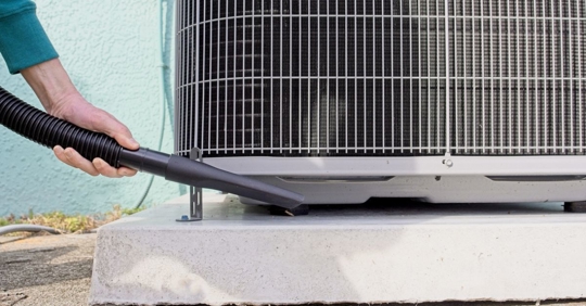 Home owner vacuums around heat pump