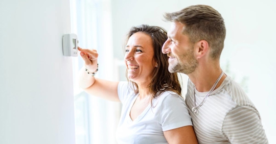 couple adjusting a thermostat