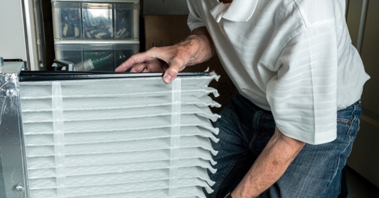 Man inserting a new air filter in a furnace